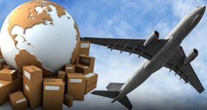 A world globe surrounded by cardboard boxes with an airplane flying overhead symbolizes global trade and air freight.